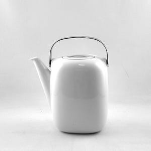 May include: White ceramic teapot with a square body and a silver handle. The teapot has a lid and a spout.