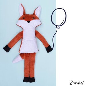May include: A plush fox toy with a white belly and black feet, lying on a light blue background. A black and white balloon is drawn in the background.
