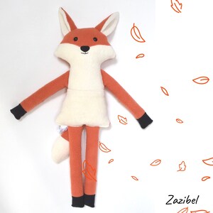 May include: A plush orange fox toy with a white belly and black feet. The fox has a long tail and is standing on a white background with orange leaf drawings.