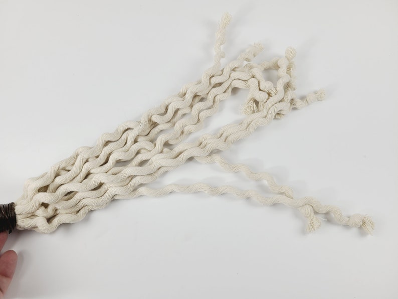 May include: A long, white, cotton rope with a brown, braided end. The rope is twisted and coiled, creating a decorative and textured look.