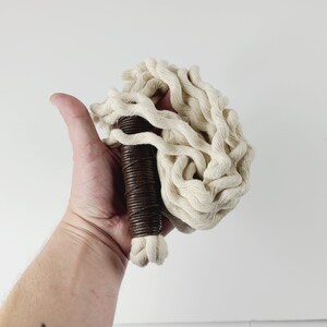 May include: A white cotton rope whip with a brown leather handle.