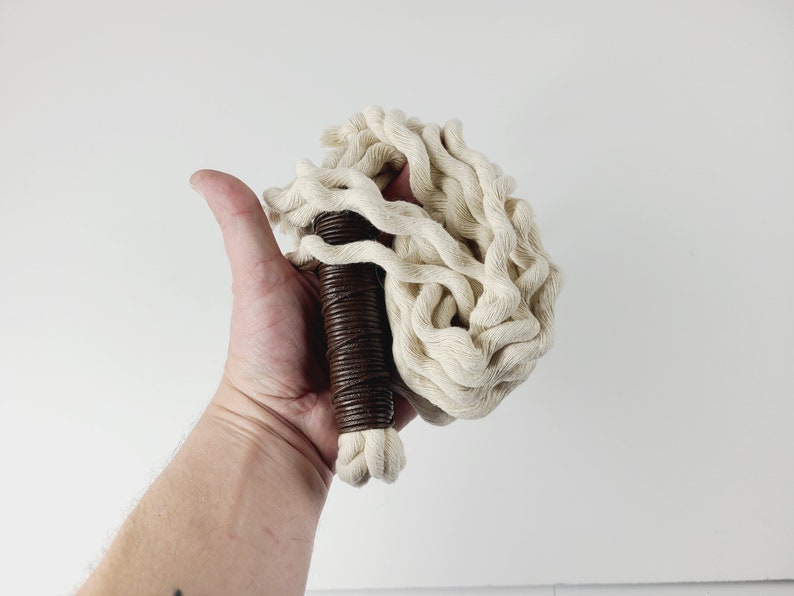 May include: A white cotton rope whip with a brown leather handle.