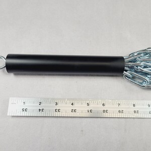 Puede incluir: Un mango de metal negro con una anilla plateada y una cadena adjunta. La cadena est&aacute; hecha de eslabones de metal plateado. Una regla se coloca junto al mango, mostrando medidas en cent&iacute;metros.