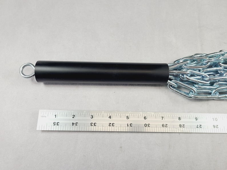 Puede incluir: Un mango de metal negro con una anilla plateada y una cadena adjunta. La cadena est&aacute; hecha de eslabones de metal plateado. Una regla se coloca junto al mango, mostrando medidas en cent&iacute;metros.