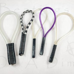 May include: Five loop-shaped implements with black taped handles. The first is clear, the second is black and white chequered, the third is thin and translucent, the fourth is purple, and the fifth is a thin, light-coloured translucent cord.