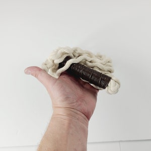May include: A white cotton rope with a brown handle. The rope is coiled and the handle is made of a brown material.