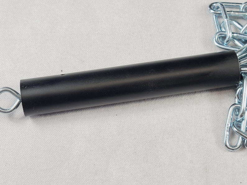 Puede incluir: Un mango cil&iacute;ndrico negro de metal con una cadena plateada adjunta. El mango es liso y tiene un peque&ntilde;o agujero cerca del centro. La cadena est&aacute; hecha de eslabones met&aacute;licos entrelazados.