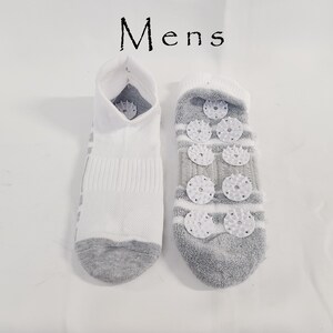 Pu&ograve; includere: Un paio di calzini alla caviglia con la scritta Mens stampata sopra. Un calzino &egrave; bianco con punta e tallone grigi, mentre l'altro &egrave; grigio con strisce bianche e presenta diversi piccoli dischi di plastica bianca testurizzati sulla suola.