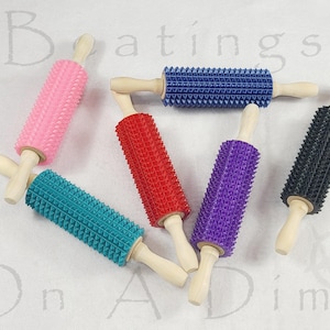 Puede incluir: Una colección de rodillos texturizados de colores. Cada rodillo tiene un mango de madera y un cuerpo cilíndrico cubierto de pequeños puntos en relieve. Los colores incluyen rosa, turquesa, rojo, morado, azul y negro. Herramientas de cocina.