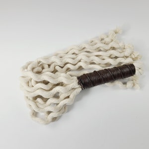 May include: A white cotton rope whip with a brown leather handle.