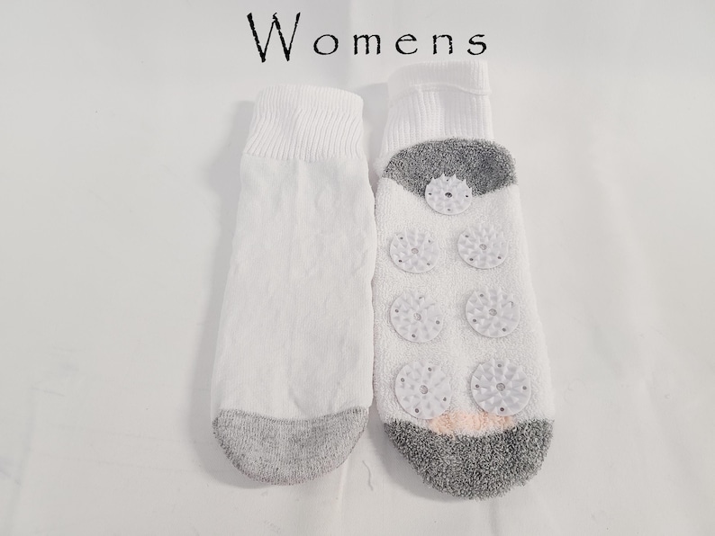 Pu&ograve; includere: Un paio di calzini bianchi con la scritta "Womens" stampata sopra. I calzini presentano punte e talloni grigi. La suola di un calzino mostra sei cuscinetti circolari antiscivolo in silicone bianco disposti su due colonne.