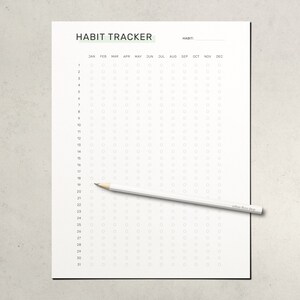 May include: A white habit tracker sheet with the title "HABIT TRACKER" and a pencil. The tracker has columns for each month and rows for each day of the month, with small circles for marking habits.