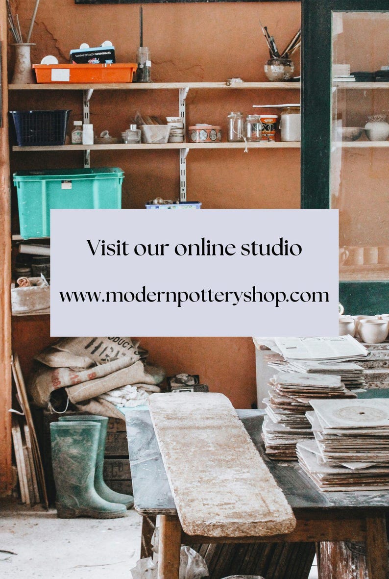 May include: A pottery studio with shelves stocked with supplies, a table with stacks of ceramic tiles, and a pair of green rubber boots. The text on the sign reads "Visit our online studio www.modernpotteryshop.com".