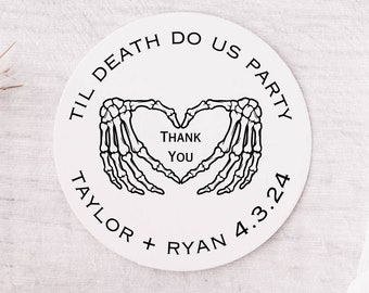 May include: Round white sticker with black text and a skeleton hand design. The text reads "Til Death Do Us Party" and "Taylor + Ryan 4.3.24". The skeleton hands are forming a heart shape with the text "Thank You" inside.