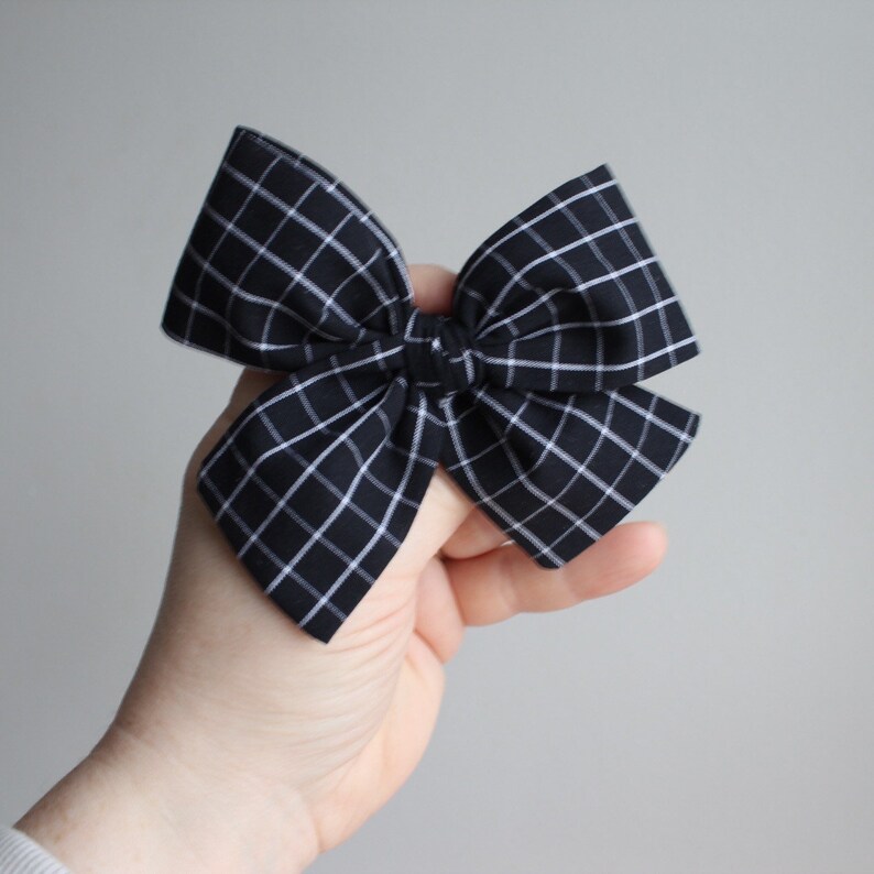 May include: A black and white plaid bow, tied in a large, symmetrical bow shape.