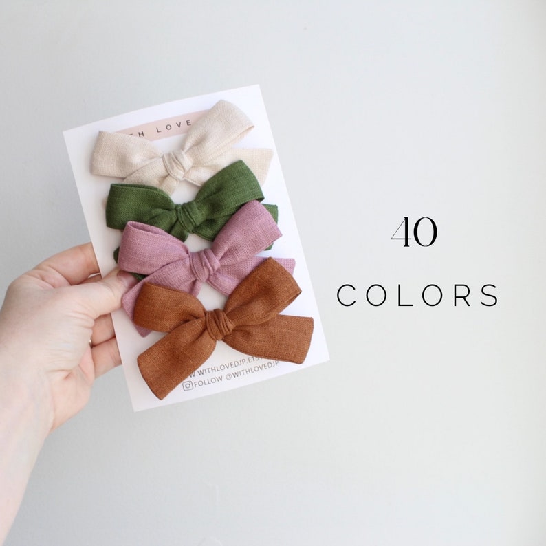 Puede incluir: Conjunto de cuatro lazos de pelo de tela en beige, verde, rosa y marr&oacute;n. Los lazos est&aacute;n dispuestos en una tarjeta blanca con el texto "With Loved" y "40 Colores".