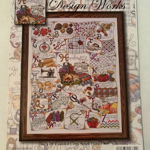 May include: A framed counted cross-stitch picture kit. The design features a patchwork of crafting-related images and words, including sewing machines, scissors, and yarn. The kit measures 16 x 20 inches.