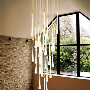 Unique staggered Ferraro Chandelier on Bronze round canopy in Foyer. High Ceiling Design Idea