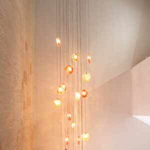 Long cascading multi color Reef Chandelier suspended by staircase on circular canopy