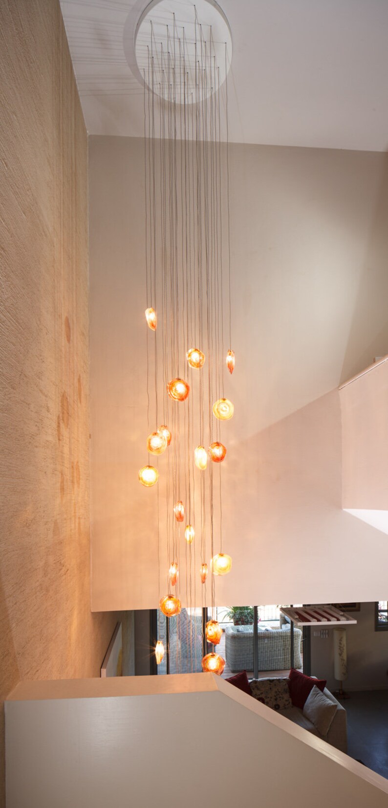 Long cascading multi color Reef Chandelier suspended by staircase on circular canopy