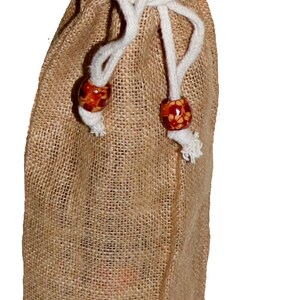 May include: A brown burlap wine bottle bag with a gold satin lining and white drawstrings with wooden beads.