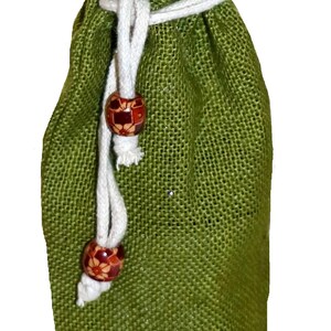 May include: A green burlap wine bottle bag with a white drawstring and wooden beads. The bag has a gold lining.