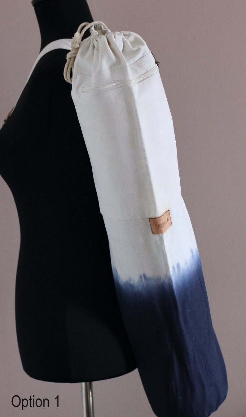 May include: White canvas yoga mat bag with a drawstring closure and a zippered pocket. The bag has a blue ombre design and a brown leather label that says "Remarkable".