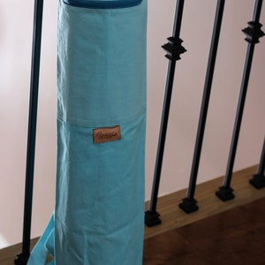 May include: A light blue yoga mat bag with a zippered pocket and a brown leather label that says "Yuka Gate".