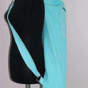 May include: A light blue yoga mat bag with a long strap. The bag is made of fabric and has a drawstring closure.