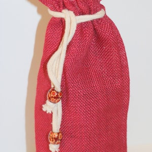 May include: Plain red burlap gift bag with a white drawstring and wooden beads. The bag has the text "(no sheer collar)" printed on it.