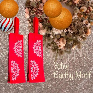 May include: Two red fabric dish towels with white embroidered mandala designs. The towels have a loop for hanging. The text "Yahvi Earthy Motif" is visible in the image.
