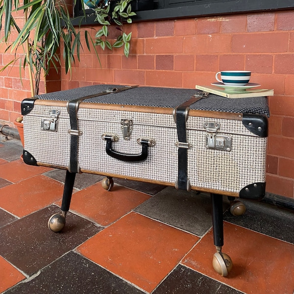 Vintage trunk/suitcase coffee table on casters. Original houndstooth body with lightly padded top upholstered in black & grey patterned wool