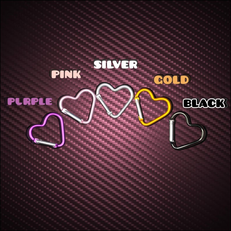 May include: Five heart-shaped carabiners arranged in a row, each featuring a different metallic finish. The colors are labeled as PURPLE, PINK, SILVER, GOLD, and BLACK. Each carabiner includes a spring-loaded gate mechanism for secure attachment.