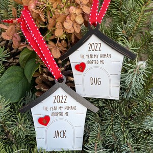 May include: Two wooden dog house ornaments with red hearts and the text "2022 The Year My Human(s) Adopted Me" and the names "Jack" and "Dug".
