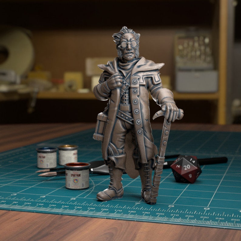 May include: A bronze painted miniature figurine of a character wearing a long coat, holding a staff and a book. The figurine is standing on a green cutting mat with paint pots and a dice.