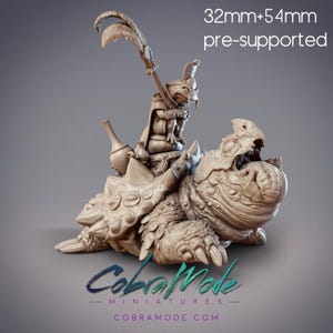 May include: A 32mm pre-supported miniature of a small, anthropomorphic creature riding a large, reptilian creature. The creature is holding a staff and has a feathered headdress. The reptilian creature has a large, open mouth and sharp claws.