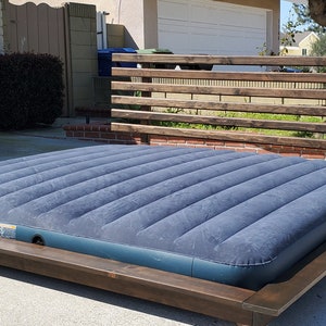 May include: A wooden platform bed frame with a dark brown stain. The frame has a slatted headboard and a blue air mattress.