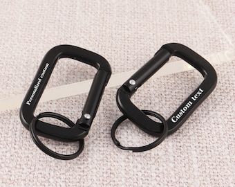 May include: Two black metal keychains with a carabiner clip and a ring. One keychain is engraved with "Personalized custom" and the other is engraved with "Custom text".