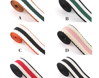 May include: Six different types of woven webbing with white and colored stripes. The webbing is rolled up and the ends are visible. The colors are green, pink, black, red, and orange.