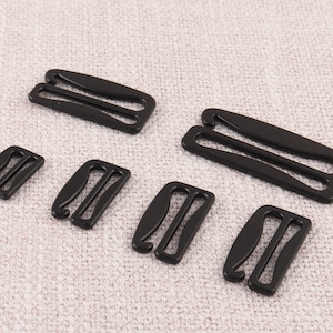 May include: Six black plastic bra strap adjusters of varying sizes.