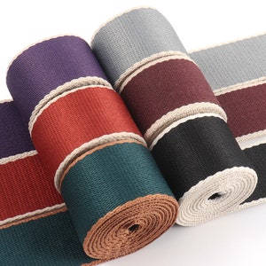 Op de afbeelding: Assortiment van geweven lint met een contrasterende bies. De linten zijn in tinten paars, rood, groen, zwart en grijs.