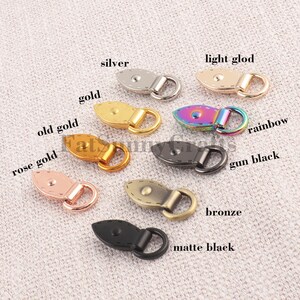 May include: A collection of decorative toggle clasps in various metallic finishes, including silver, gold, rose gold, and gun black. Each clasp features a rounded, stitched design with a loop for attachment. The image also includes a rainbow and bronze clasp.