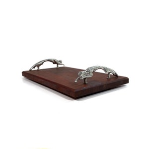 May include: A rectangular wooden serving tray with two cheetah-shaped handles. The tray is made of dark wood and the handles are silver.