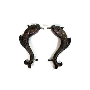 Könnte beinhalten: Ein Paar antike bronzene Türklinken in Fischform. Die Griffe sind detailliert gestaltet und in gutem Zustand.