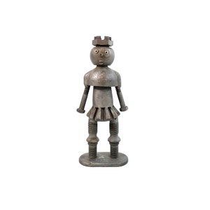 May include: A metal figurine of a person with a crown, made from nuts and bolts. The figurine has a round head with a face, and the body is made from various metal parts.