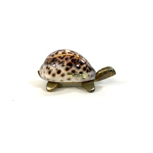 Peut inclure: Une petite tortue décorative en coquillage brun et blanc avec des accents en laiton. La tortue est fabriquée à Maurice.