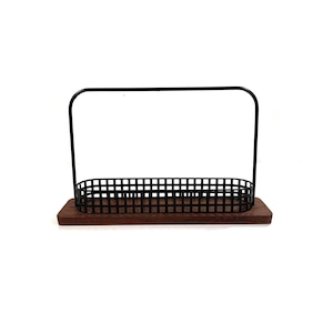 May include: A black metal wire rack with a wooden base. The rack has a rectangular shape and is designed to hold items like bottles or other kitchen supplies.