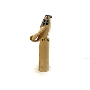 Könnte beinhalten: Holzskulptur eines Falken, der auf einem zylindrischen Sockel sitzt. Der Falke hat detaillierte schwarz-weiße Markierungen auf Kopf und Flügeln, mit gelben Akzenten an den Krallen. Die Skulptur ist aus hellem Holz gefertigt.