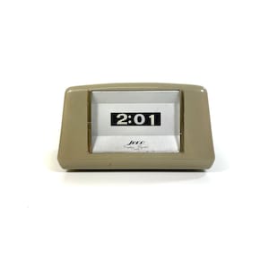Könnte beinhalten: Eine beige Flip-Clock mit schwarzen Zahlen, die 2:01 anzeigen. Die Uhr hat einen goldenen Rahmen und der Text "Jecco Cordless Digital" ist auf dem Zifferblatt aufgedruckt.