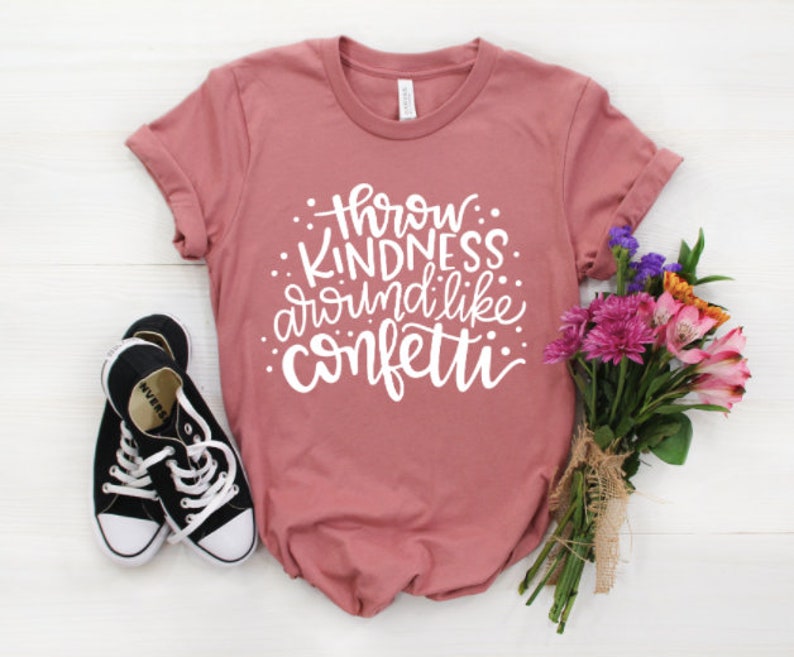 May include: A dusty rose t-shirt with the text "Throw Kindness Around Like Confetti" in white lettering.